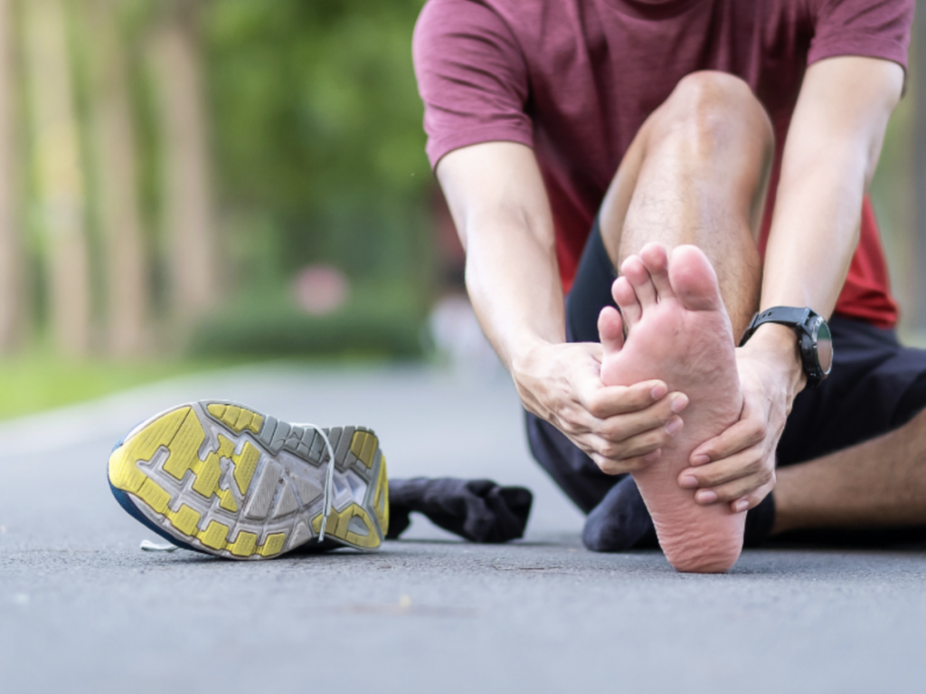 Runner sitting on the road rubbing his foot