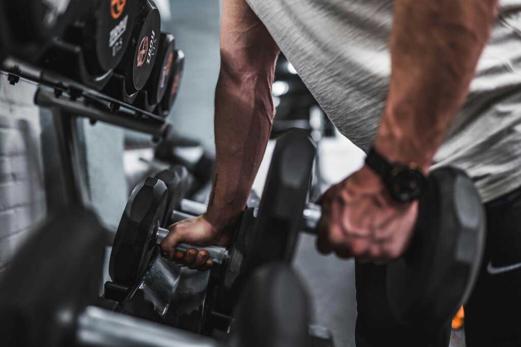 man in grey shirt holding dumbbell