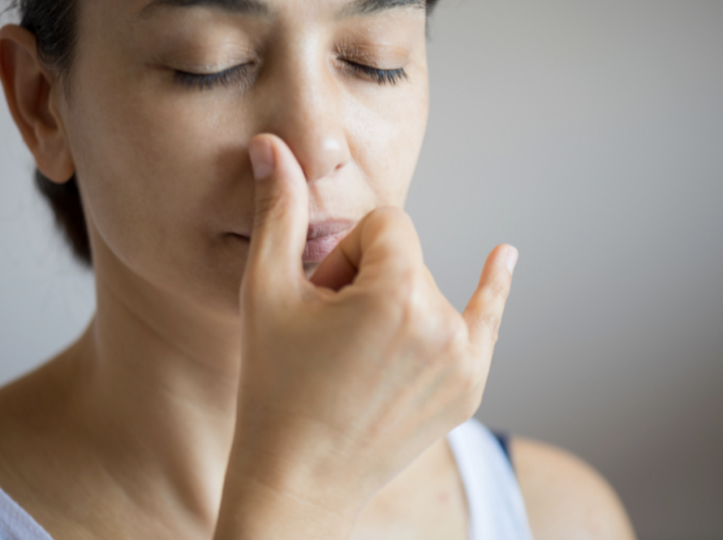 woman with eyes closed covering one nostril for alternate nostril breathing