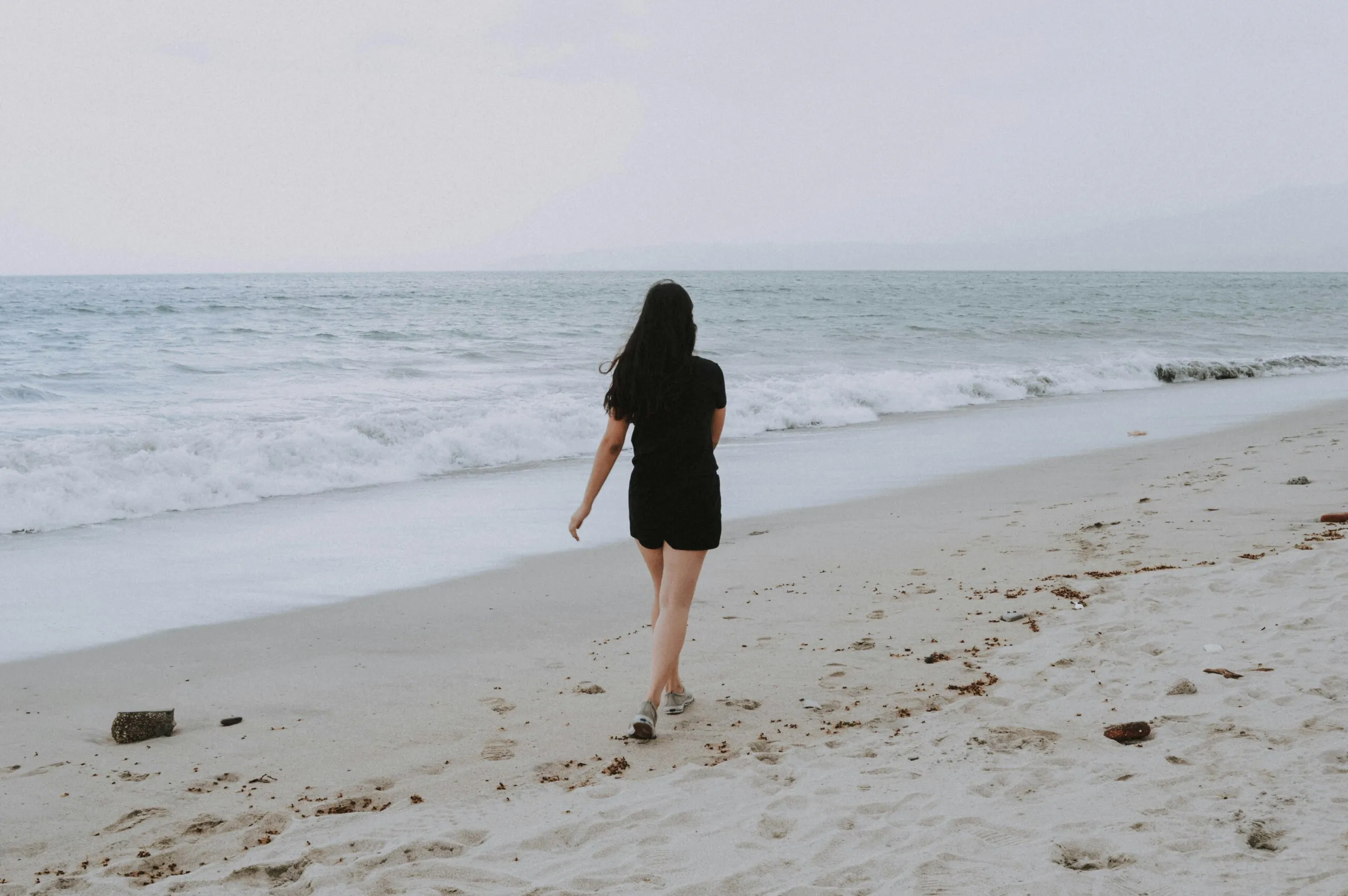 Woman standing on the beach looking at the ocean 